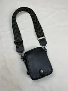 Detail view of men's vertical crossbody bag featuring wide geometric strap and durable black PU leather.