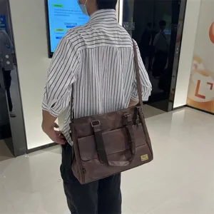 Vue détaillée du sac bandoulière d'affaires marron pour homme avec poches avant et lanière.