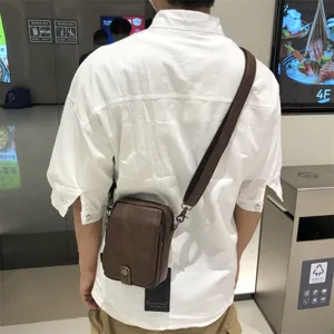 Brown leather vertical crossbody bag detail shot, casual style daily shoulder bag for men.