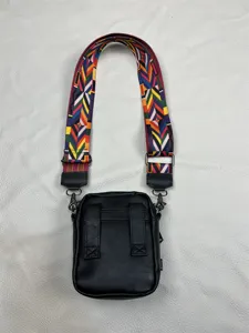 Close-up detail of the black vertical crossbody bag featuring vibrant geometric woven strap.