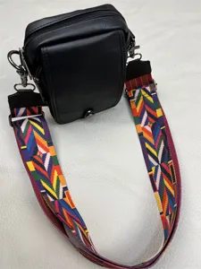 Detailed close-up view of the black cross body bag featuring a vibrant colorful woven strap.