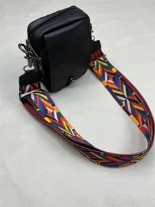 Men black vertical crossbody bag detail shot, wide colorful strap minimalist shoulder bag.