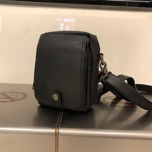 Detailed view of the black PU leather vertical crossbody bag, showing the front flap and hardware.