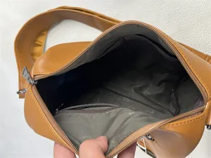 Brown PU leather crossbody bag interior detail showing spacious compartment and lining.