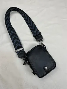 Detailed view of the black men vertical crossbody bag with wide chevron patterned shoulder strap.