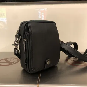 Black leather vertical crossbody bag detail showing front flap and adjustable strap.