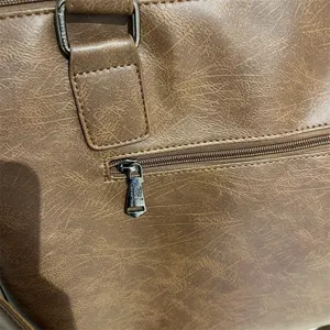 Gros plan sur la fermeture éclair et la quincaillerie du sac d'affaires pour hommes marron.