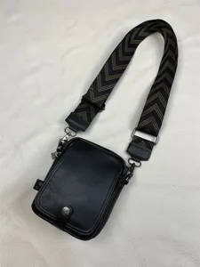 Detail shot of black men vertical crossbody bag with wide chevron patterned canvas shoulder strap.