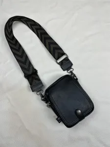 Black vertical crossbody bag detail, wide chevron strap, durable leather, casual style.