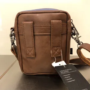 Detail view of the brown leather vertical men shoulder bag back with strap hooks and brand tag.