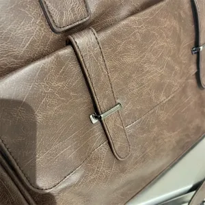 Detail de sac d'affaires en cuir PU marron, bouclage metallique et surface texturee en gros