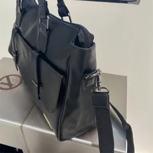 Sac d'affaires homme en cuir noir avec bandoulière et poche avant pour ordinateur.