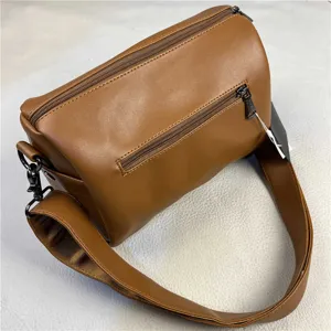 Brown cylindrical crossbody bag with multiple zippers and wide strap for daily commute.