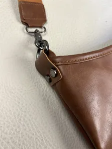 Detailed close-up shot of brown leather men shoulder bag with metal hardware and strap.