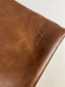 Brown faux leather bag detail shot showing fine texture and debossed brand logo craftsmanship.
