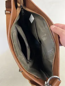 Detail view of the brown leather shoulder bag interior, showing pockets and lining.
