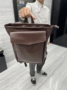 Detail view of the brown leather backpack, showcasing front pocket design and durable build.