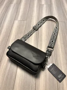 Stylish black PU leather crossbody bag for men featuring wide woven geometric shoulder strap.