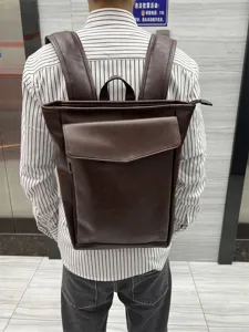 Back view detail of brown leather backpack, showing adjustable straps and front flap pocket.