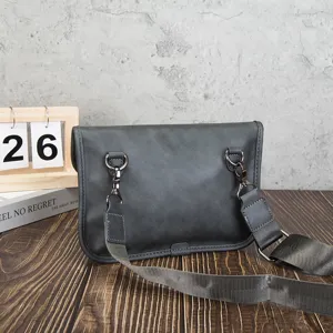 Detailed view of the dark grey soft leather messenger bag with metal hardware and strap.