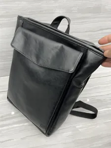 Black PU leather backpack detail view showing front flap pocket and top handle construction.