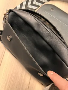 Detail view of casual men's black PU leather crossbody bag with zipper and wide strap.