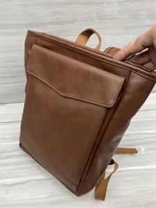 Brown leather casual backpack for men and women, stylish school bag with front pocket detail.
