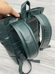 Dark green leather backpack detail view showing strong straps and top handle construction clearly.