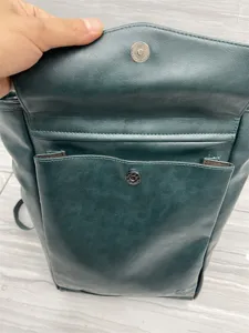 Detail view of dark green PU leather backpack front pocket and magnetic snap closure.