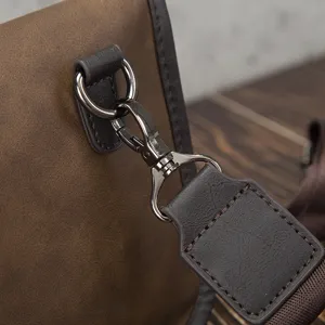 Close-up detail of retro brown men shoulder bag hardware metal hook and PU leather strap connection.