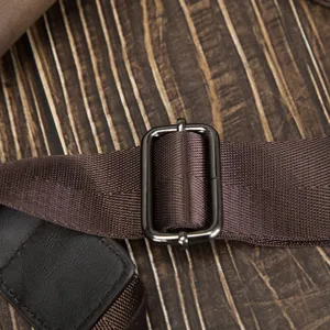 Detail shot of adjustable brown bag strap with metal buckle and woven texture.