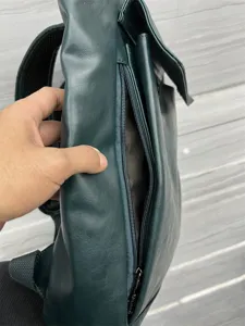 Dark green faux leather backpack detail showing side zipper pocket and quality texture.