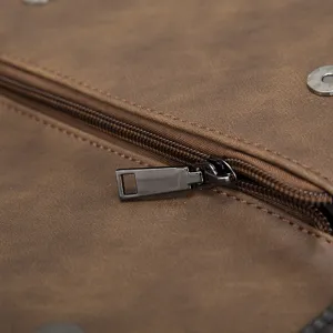 Close-up detail of brown soft leather men bag showing zipper and metal magnetic snap hardware.