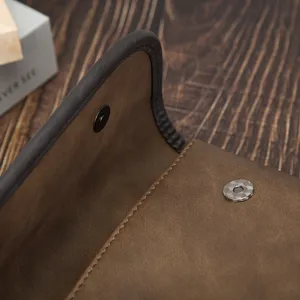Detailed shot of brown leather vintage men's crossbody bag with magnetic snap and fine stitching.