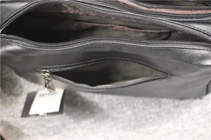 Detail view of black leather crossbody bag for men, featuring multiple metal zippers and pockets.