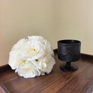 Detailansicht des künstlichen weißen Rosenstrauchs mit schwarzer Vase für Heimdekoration.