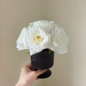 Nahaufnahme Detail des weißen künstlichen Rosenstrauchs in schwarzer strukturierter Vase.