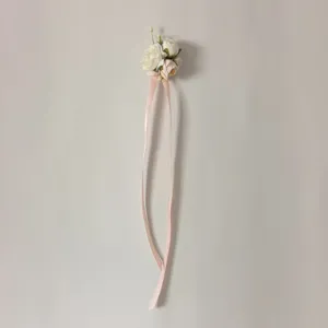 Detailed close-up view of elegant pink artificial flower corsage with long ribbon details.