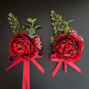 Detailed close-up of red artificial flower boutonnieres with green foliage and ribbons.