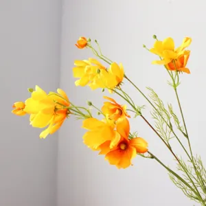 Close-up detail of artificial yellow cosmos flower branch, realistic silk floral decor.