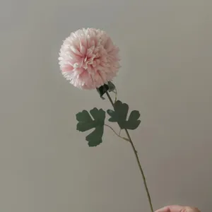 Artificial pink flower detail view, realistic stem and green leaves for photography props.