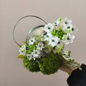 Detailed close-up of handmade artificial flower bouquet with white blooms and green foliage decor.