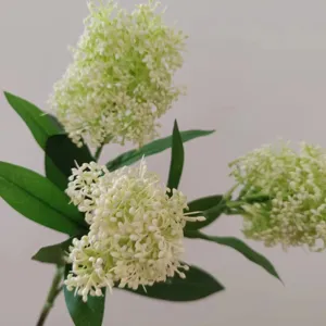 Detailed close-up shot of artificial skimmia flower branch with green leaves for home decor.