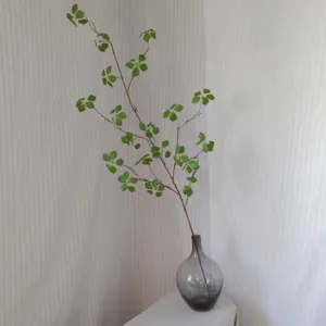 Artificial green plant branch in glass vase for home decor interior styling detail.