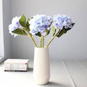 Fiori artificiali di ortensia blu in seta in un vaso di ceramica bianca per decorare la casa.