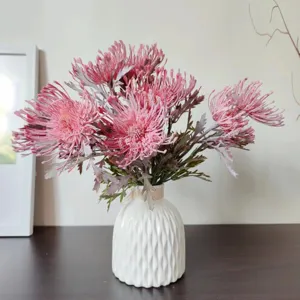 Vista dettagliata di un mazzo di fiori di cuscino artificiali floccati in vaso di ceramica bianca.