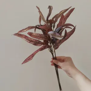 Primo piano di foglie di eucalipto autunnali artificiali con piccole bacche per decori.