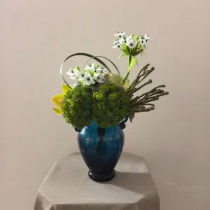 Artificial flower bouquet detail, blue glass vase for home decor and photography display.