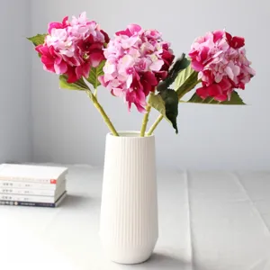 Primo piano di ortensie artificiali in un vaso bianco scanalato per decorazioni.