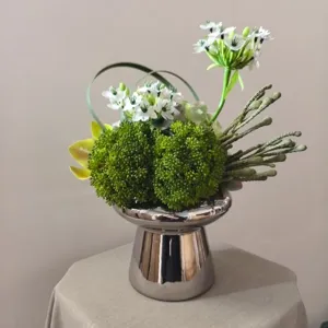 Modern artificial flower bouquet centerpiece with silver vase for home decor photography.